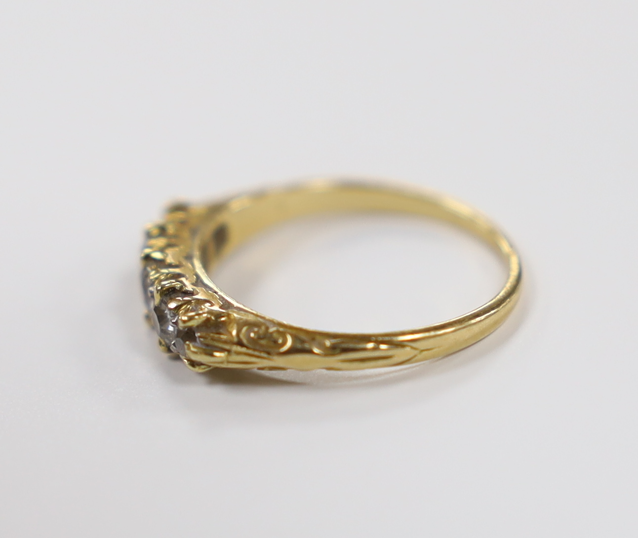 An early 20th century yellow metal and graduated five stone diamond set half hoop ring, size I, gross weight 2.1 grams.